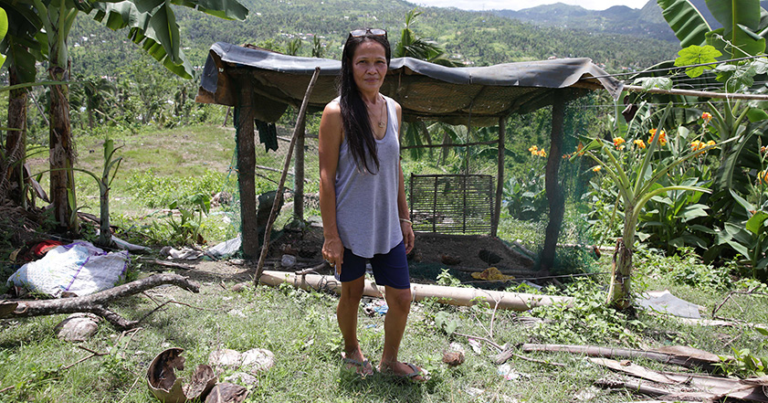 Woman standing next to damaged building in the Philippines