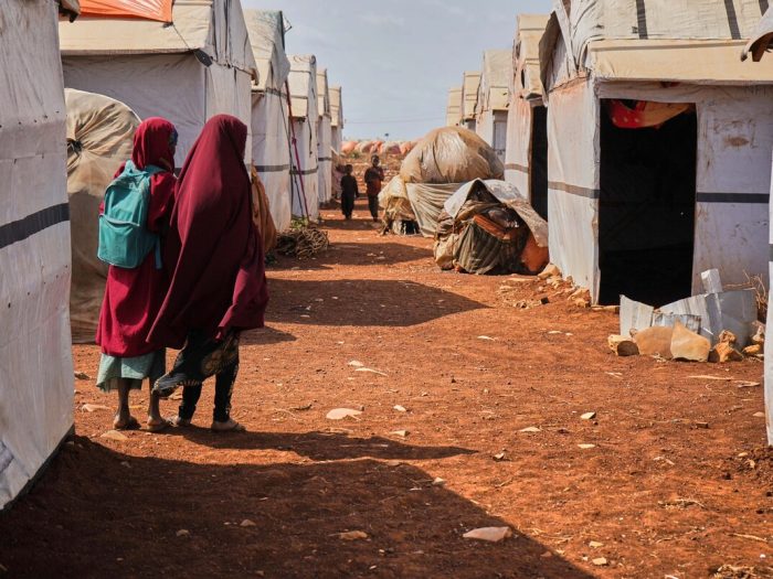 People walking among shelters in a displacement camp in Somalia