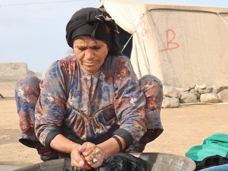 Woman washing clothes in a displacement camp in Syria