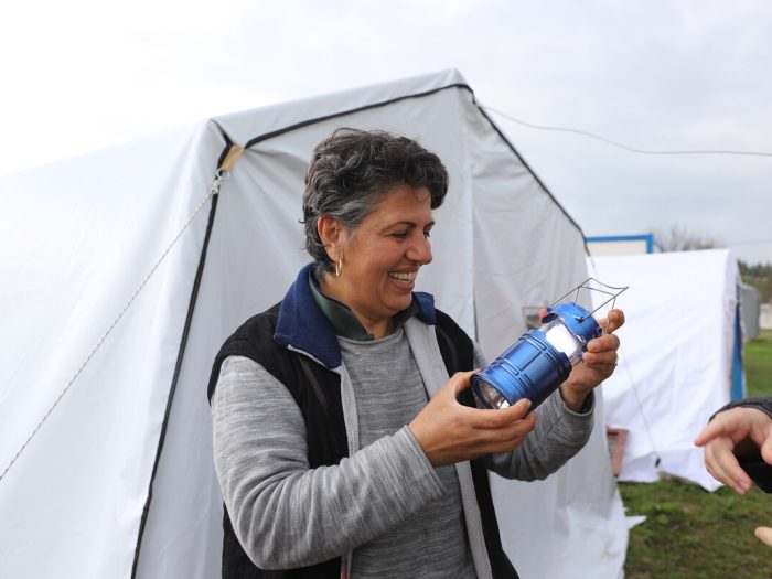 Woman holding solar light outside a tent in Turkey