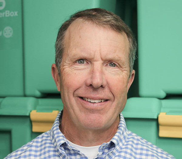 Man wearing blue and white checked shirt in front of green boxes