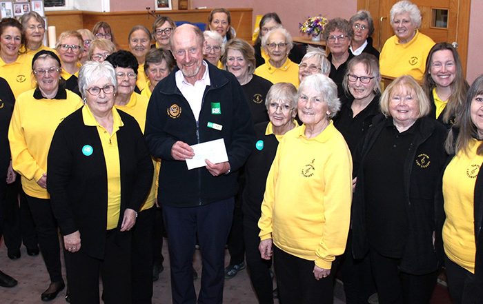 Group of people wearing yellow and black, one holding a cheque