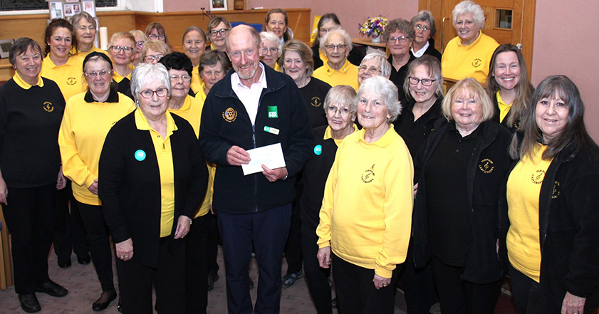 Group of people wearing yellow and black, one holding a cheque