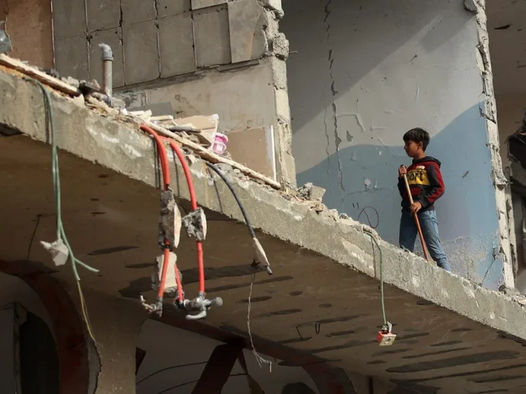 Boy sweeping a room inside a damaged building in Gaza