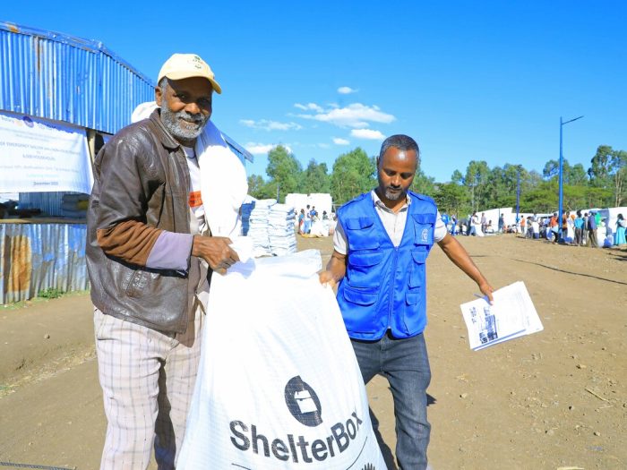 Two men carrying a bag of aid