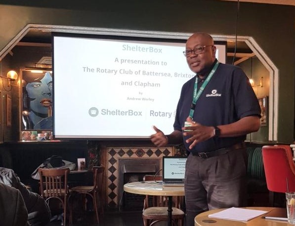 Man next to display screen giving a talk on ShelterBox