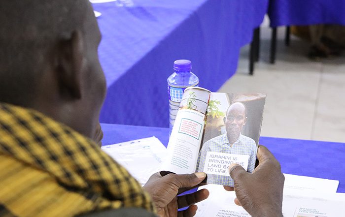 Man from Somalia looking at booklet with a picture of himself inside