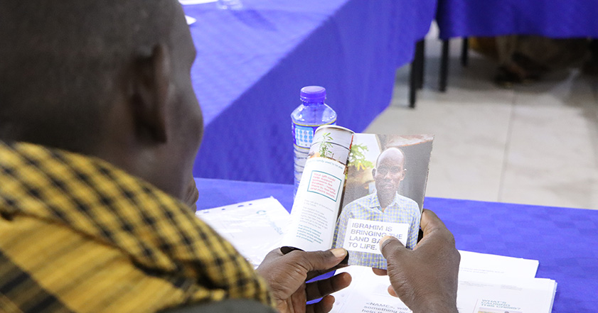 Man from Somalia looking at booklet with a picture of himself inside