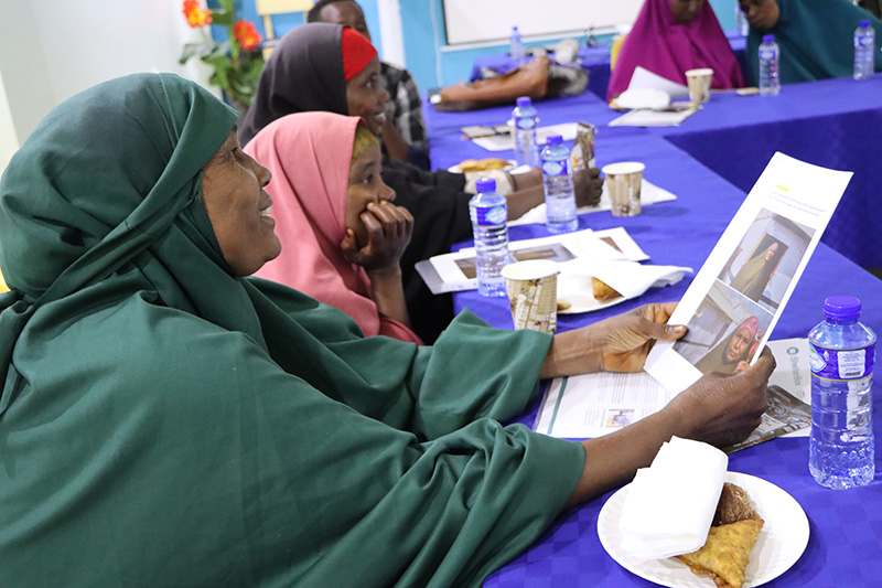 Woman seated at a table, looking at a piece of paper with images of her.