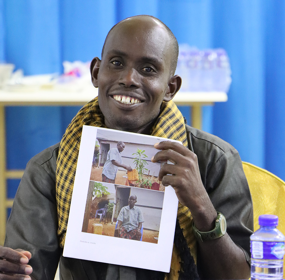 Man smiling at the camera holding a piece of paper with images of himself