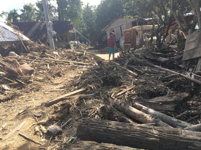 Damaged buildings next to a road covered in mud and debris in the Philippines