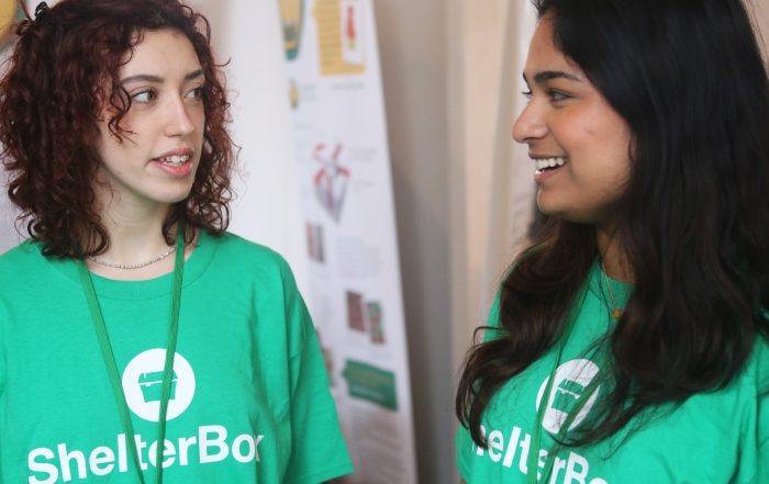 Two women in conversation wearing ShelterBox t-shirts