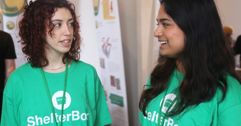 Two women in conversation wearing ShelterBox t-shirts