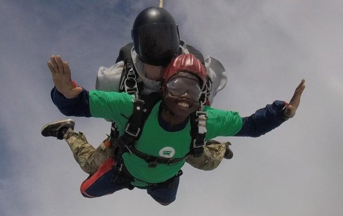 A young man in the air, skydiving with an instructor behind him