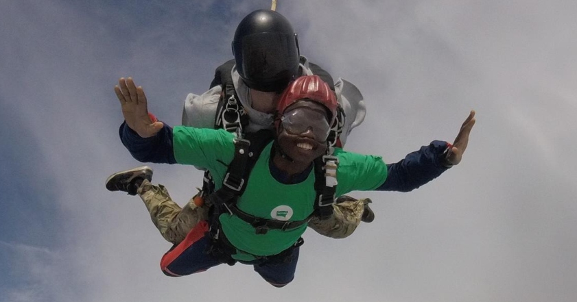 A young man in the air, skydiving with an instructor behind him