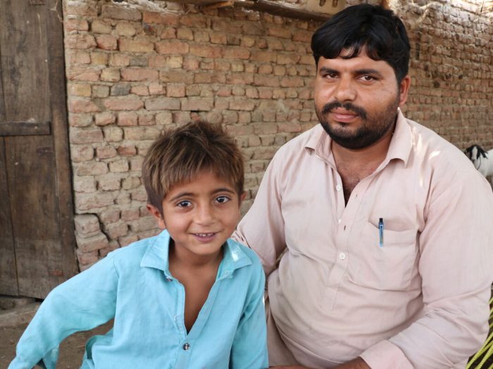 Man and boy sitting in front of a house in Pakistan