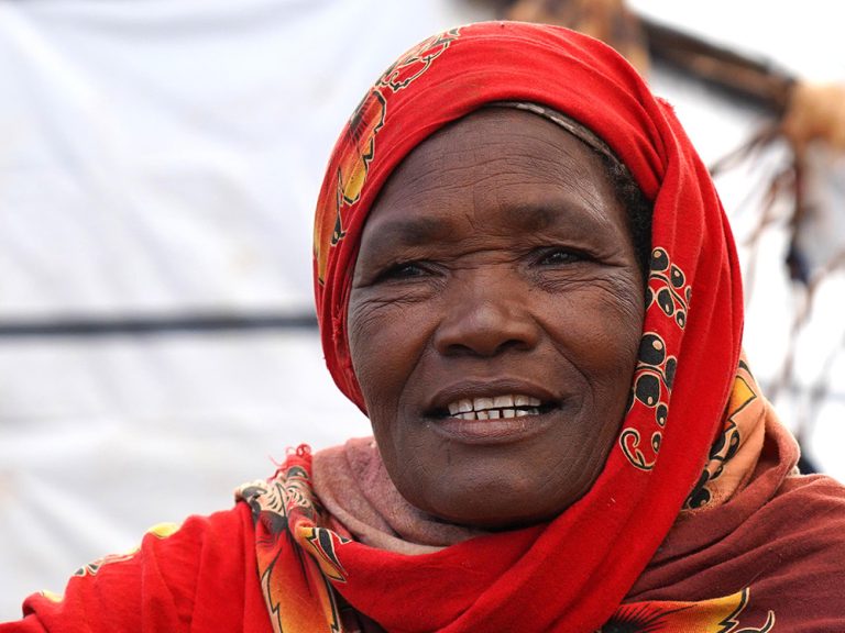 Woman wearing red head scarf in front of shelters in Somalia