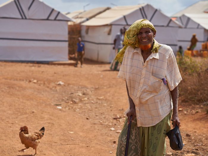 Man standing next to shelters and a chicken in Somalia