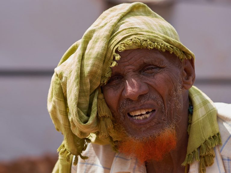 Man wearing green head scarf in front of tents in Somalia