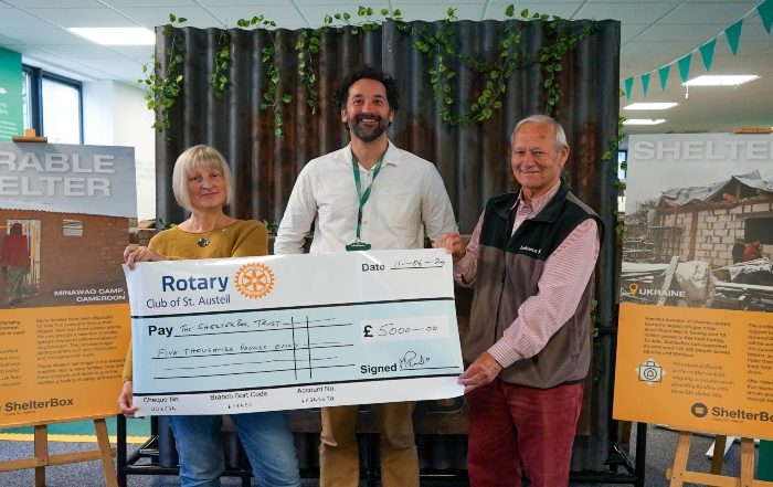 Three people holding a large cheque for ShelterBox