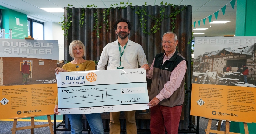 Three people holding a large cheque for ShelterBox