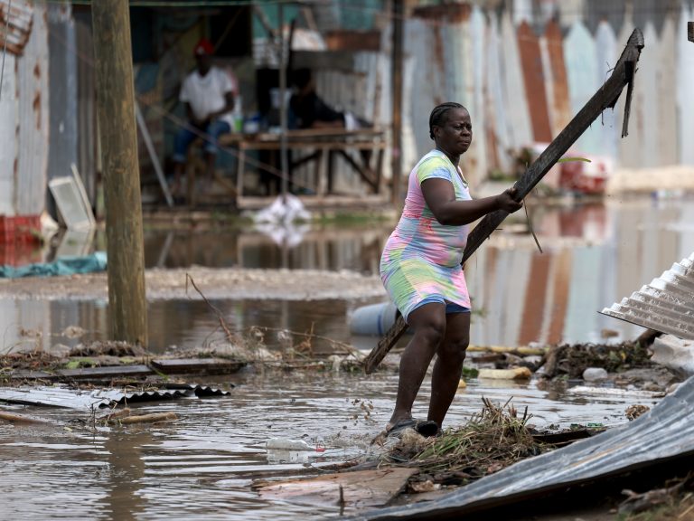 Woman moving rubble in the Caribbean after Hurricane Beryl