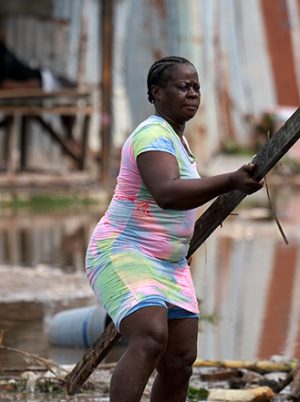 Woman moving rubble in a destroyed house in the Caribbean after Hurricane Beryl