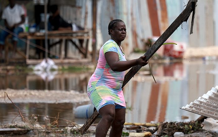 Woman moving rubble in a destroyed house in the Caribbean after Hurricane Beryl