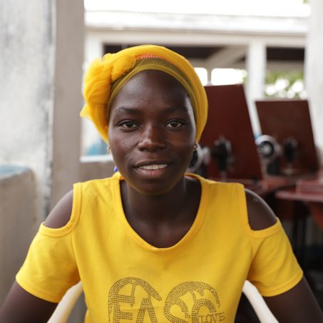 Woman in yellow with a yellow turban smiling at the camera