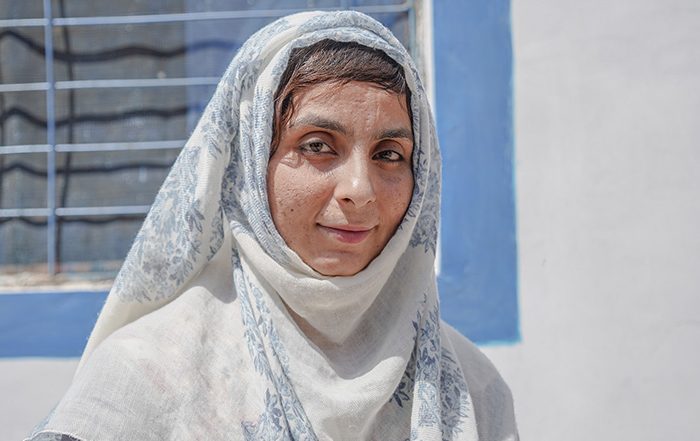 Woman wearing white and blue headscarf smiling at the camera