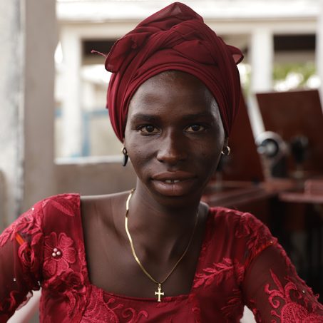 Lady in red with a red turban smiling at the camera