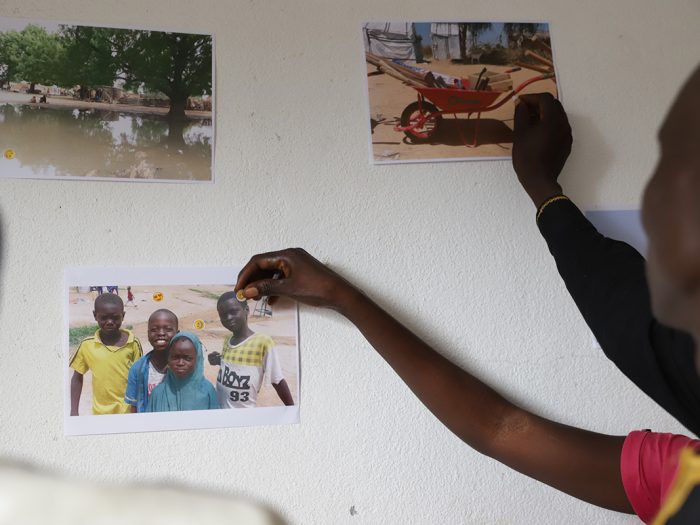 People putting emoji stickers on photos on a wall