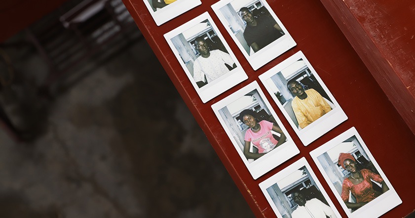 Polaroid photos of people in Cameroon laid out on a table