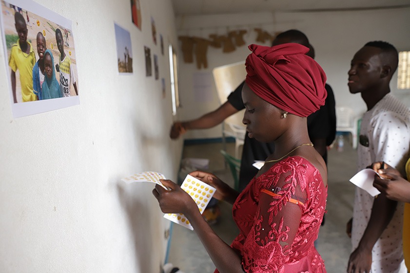 Woman with emoji stickers standing next to wall with photographs on it