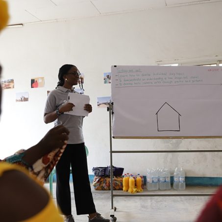 Two people stood next to a whiteboard in a workshop in Cameroon