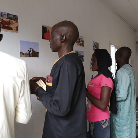 People standing next to a wall with photographs on it