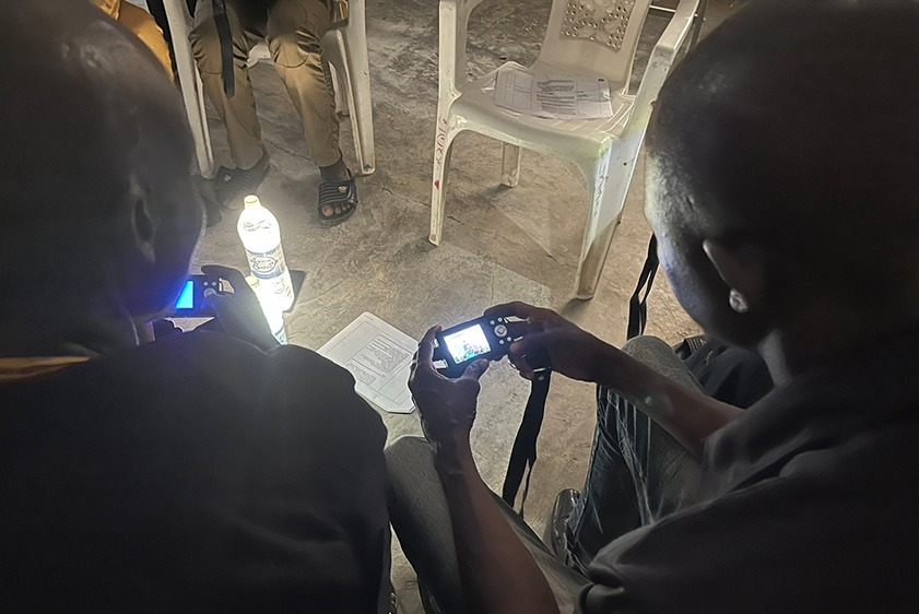 People using a camera while a water bottle is stood on a mobile form to make a lamp