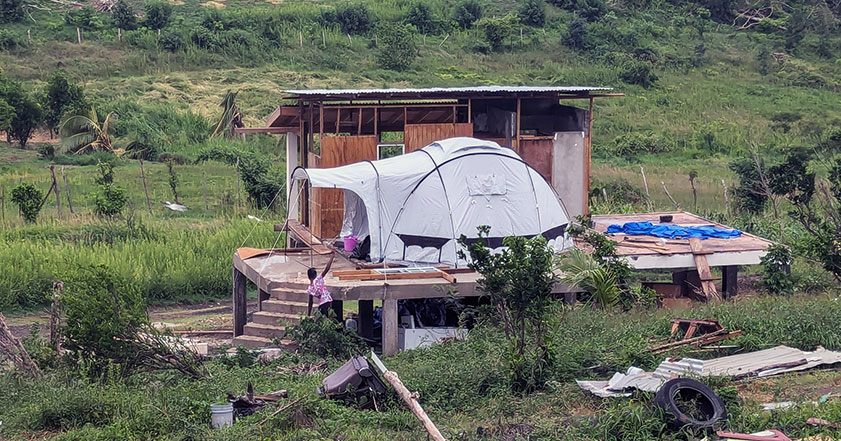 A ShelterBox tent pitched next to a damaged home after hurricane beryl