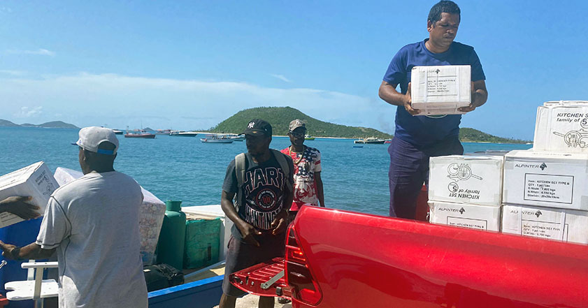 Four men unpack aid items from a red pick up truck after hurricane beryl