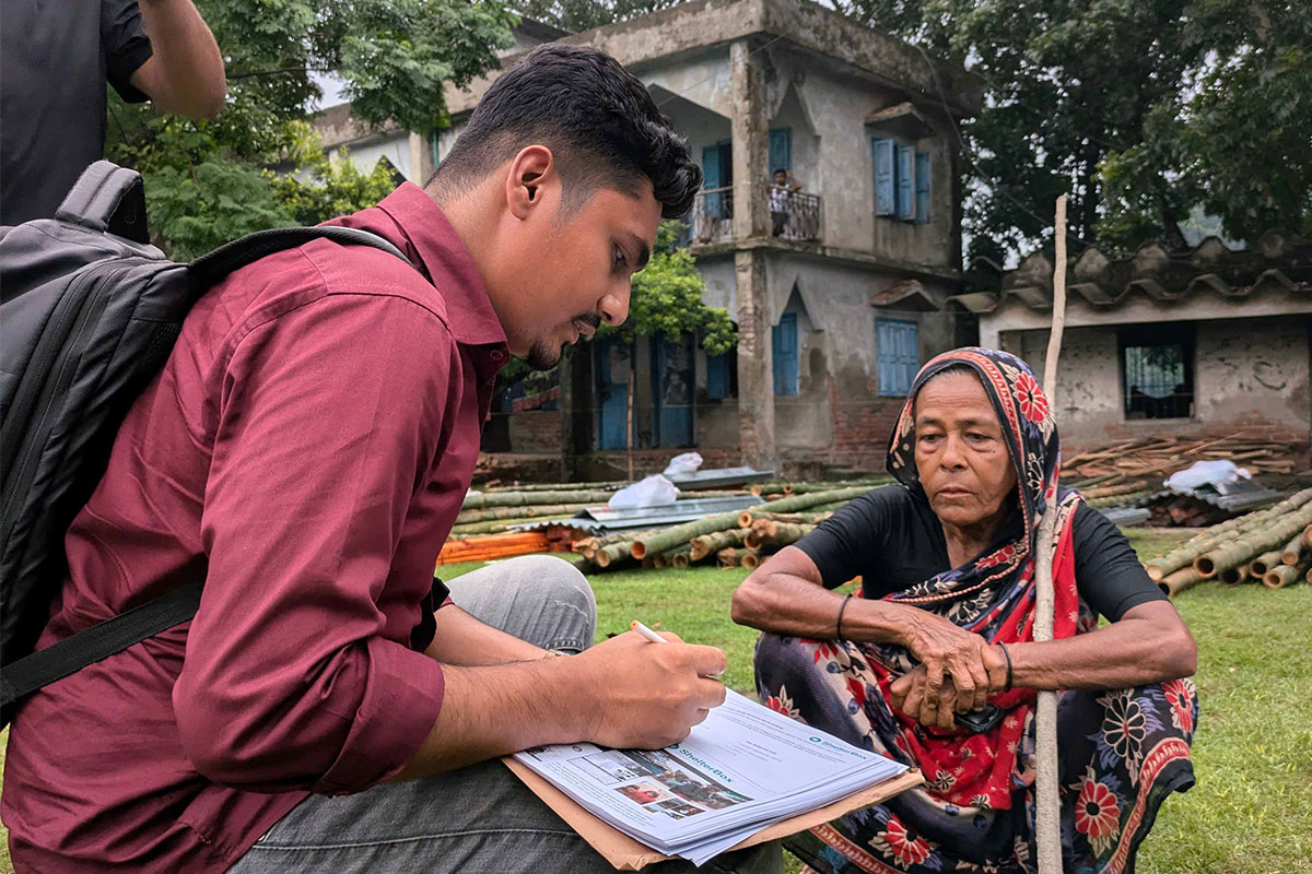 Man making notes whilst talking to woman in Bangladesh