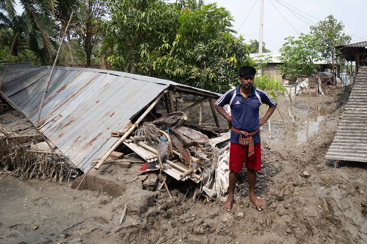 Man stands by collapsed home in floodwater in Bangladesh