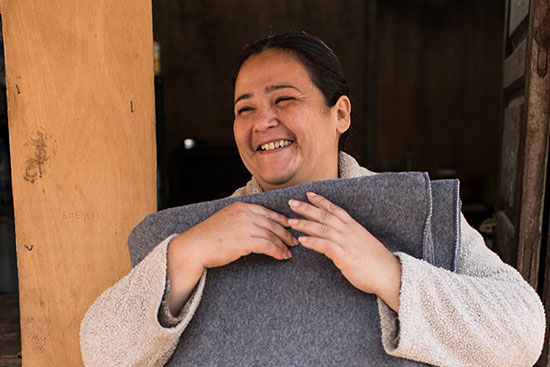 Woman smiles hugging grey blanket in paraguay