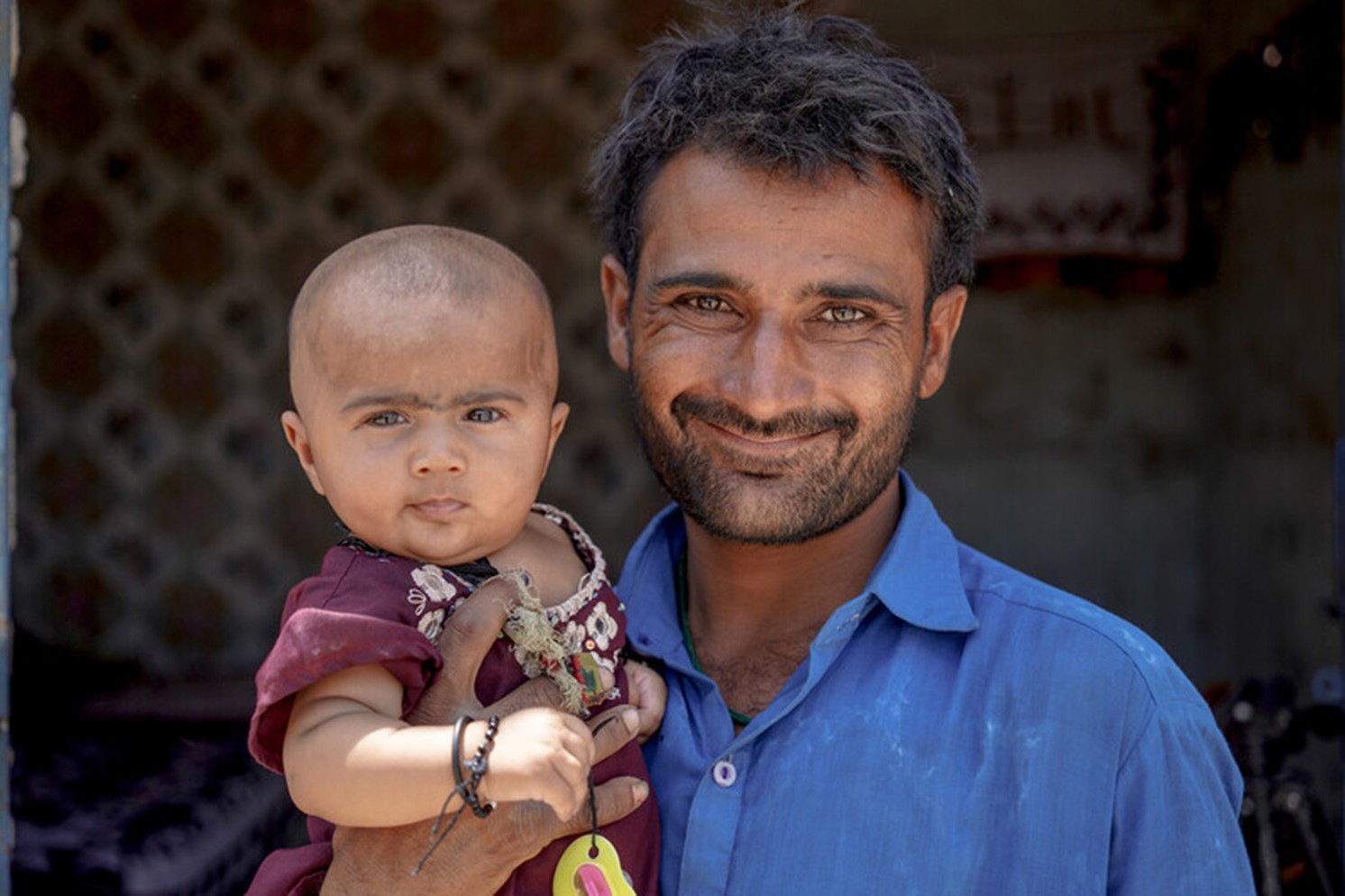 Ali and his baby, in front of their new home. Sindh Province, Pakistan.